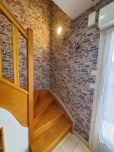 a staircase in a brick walled room with wooden stairs at La vie là in Saint-Georges-sur-Eure