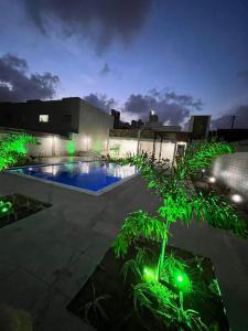 een huis met een zwembad met groene verlichting bij Casa confortável à 568m da praia de Ponta Negra in Natal