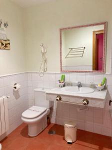 Un baño con lavabo, inodoro y espejo. en Posada La Casona de Los Güelitos, en Santillana del Mar