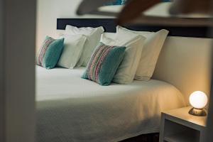 a bed with white pillows and a lamp on a table at Breathe In in Zambujeira do Mar