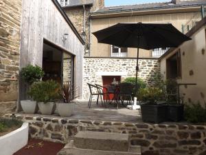 un patio con mesa y sombrilla en HOTEL particulier LARIBOISIERE en Fougères