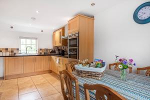 a kitchen with a table and a clock on the wall at Eveley Cottage in Boscastle