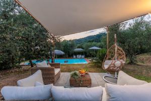 patio con sofá, columpio y piscina en Villa Dondolino, a Stylish Farmhouse en Lucca