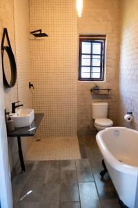 The Mustard Seed Guesthouse في بلومفونتين: حمام مع حوض ومغسلة ومرحاض