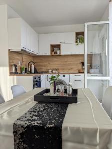 a kitchen with white cabinets and a table with a sink at Уютен двустаен апартамент с прекрасна гледка in Stara Zagora