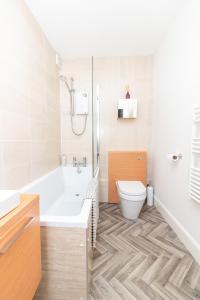 a bathroom with a tub and a toilet and a sink at D'City Apartment, up to 6 guests in Dundee