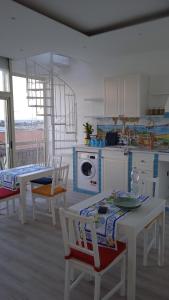 a kitchen with white tables and chairs and a kitchen with a stove at Donna Sicilia 2 in Giardini Naxos