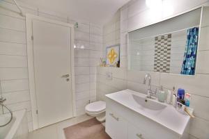 ein Badezimmer mit einem Waschbecken, einem WC und einem Spiegel in der Unterkunft Стильные апартаменты Dotan in Netanya