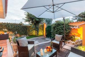 une terrasse avec un parasol, des chaises et une table dans l'établissement Corallina, 2 Bedrooms Villa with Garden and Private Jacuzzi, à Torvaianica