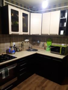 cocina con armarios negros, fregadero y microondas en Апартаменты на набережной в Актау, en Aktau