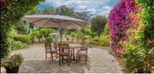 um pátio com uma mesa, cadeiras e um guarda-sol em Domaine des Tuilières avec piscine em Vallauris