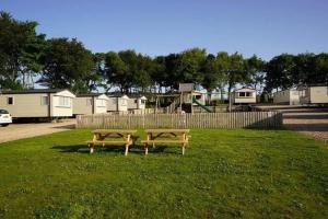 two benches sitting in the grass in a park at Wrights Retreat 4 Lunan View St Cyrus Caravan Park in Saint Cyrus