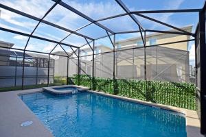 - une piscine en face d'une maison en verre dans l'établissement Amazing 6BR Villa @ Storey Lake Resort Near Disney, à Kissimmee