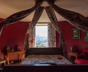 a bedroom with a canopy bed with a window at Château de Pramenoux in Lamure-sur-Azergues