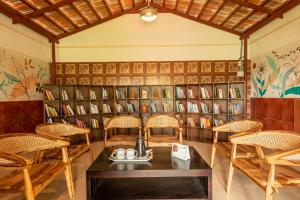biblioteca con mesa, sillas y estanterías en Anvesana I Yoga Spa Retreat, en Dod Ballāpur