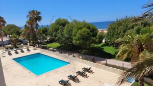a swimming pool with chairs and the ocean in the background at Apartamento Kélyfos Beach by feriascomsol in Quarteira