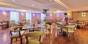 a woman standing in a restaurant with tables and chairs at Les Rocquettes Hotel in St. Peter Port