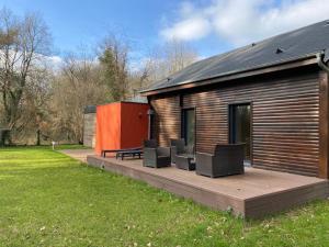 une maison avec une terrasse munie de chaises dans l'établissement Magnifique lodge dans la forêt de Fontainebleau, à Arbonne