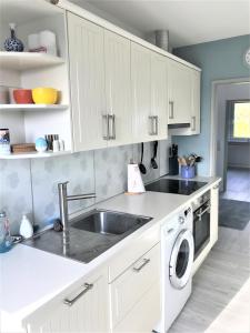 eine weiße Küche mit einer Spüle und einem Geschirrspüler in der Unterkunft Ferienwohnung Sonnendeck in Eckernförde