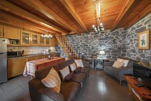 ein Wohnzimmer mit Sofas und einer Steinmauer in der Unterkunft Refúgio da Serra - By WeHost in Ribeira do Raposo