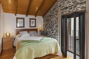 um quarto com uma cama e uma parede de pedra em Refúgio da serra em Arco da Calheta