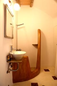 a bathroom with a sink and a wooden chair with a mirror at Panormos Art Villas & Suites in Pánormos