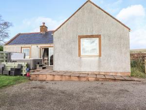 a brick house with a window and a patio at Grey Craig Cottage in Lockerbie