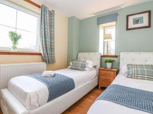 2 camas en un dormitorio pequeño con ventana en Grey Craig Cottage en Lockerbie