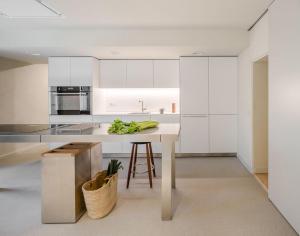 uma cozinha com armários brancos e uma mesa com vegetais em Casa Fàbregas - Benestar Natural em Viladrau