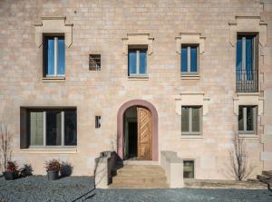- une façade en briques avec une porte en bois dans l'établissement Casa Fàbregas - Benestar Natural, à Viladrau