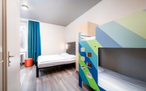 a small room with a bunk bed and a bedroom with a bed at a&o Wien Stadthalle in Vienna