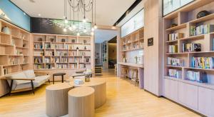 a library with two tables and shelves of books at Atour Hotel Suzhou Jinji Lake Ligongdi in Suzhou
