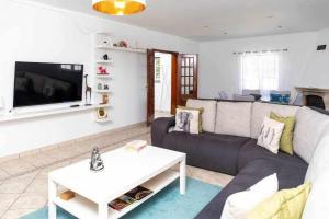 a living room with a couch and a tv at Nuvem Cristina c piscina Óbidos 3 quartos in Olho Marinho