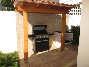 a barbecue under a wooden pergola on a patio at Villa Hansen in Garajau - Cristo Rei in Caniço
