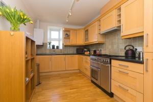 a kitchen with wooden cabinets and stainless steel appliances at Sand Dunes 6 The Manor in St Ives
