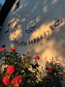 a sign on the side of a building with red roses at Landgut Voigtsmühle in Friedland