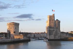 a castle with two towers on a river at Appartement T2 lumineux et cosy au calme proche du centre avec TV Netflix et Wifi in La Rochelle