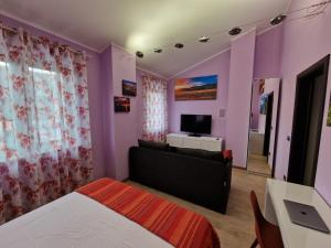 1 dormitorio con paredes de color púrpura, 1 cama y TV en W a n d e r l u s t - casa con piscina riscaldata ad uso esclusivo - Marche, en Rustico