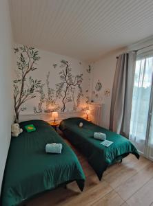 two beds in a room with green sheets at Atelier des sens 89 in Évry