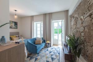 - un salon avec une chaise bleue et un mur en pierre dans l'établissement Charm Luxury House, à Porto