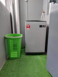 - une poubelle verte à côté d'un petit réfrigérateur dans l'établissement Hanis Homestay De Bangi, à Kajang
