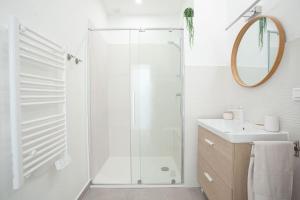 La salle de bains blanche est pourvue d'une douche et d'un lavabo. dans l'établissement Duplex Mandelieu, à Mandelieu-la-Napoule
