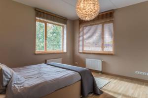 um quarto com uma cama, 2 janelas e um lustre em STUNNING 2 BEDROOM APARTMENT IN QUITE PART OF RIGA em Riga