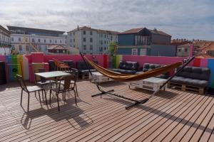 a hammock on top of a roof with furniture at CATS Porto Hostel in Porto