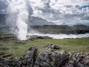 a geyser in a field next to a body of water at La Casina de la Huerta in Llanes