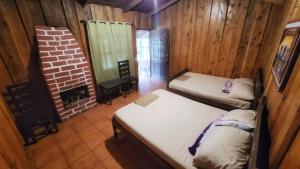 a room with two beds and a brick fireplace at Hotel de Montaña Buena Vista in Río Chiquito