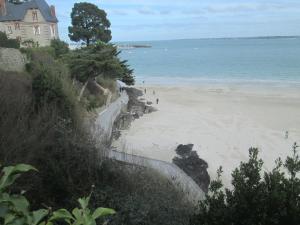una playa con una casa y gente caminando por la arena en TY PLAGE, en Saint-Cast-le-Guildo