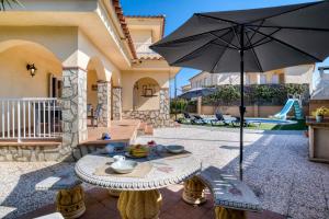 a patio with a table and an umbrella at Vela, casa con piscina privada a pocos metros de la playa in L'Escala