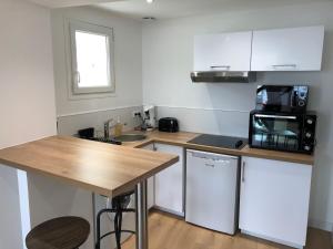 una pequeña cocina con encimera de madera y microondas en TERRA Studio cosy et calme proche du centre avec parking TV Netflix et Wifi, en La Rochelle