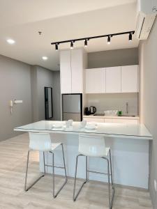 a kitchen with a white counter and white chairs at Atria Sofo Suites - Petaling Jaya in Petaling Jaya
